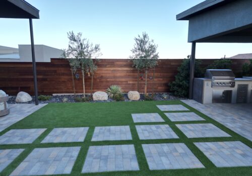 A backyard with grass and concrete tiles