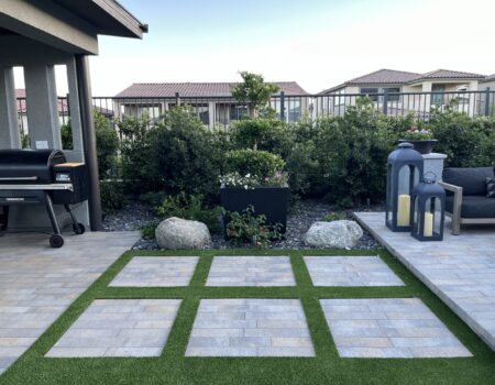 A patio with grass and a large square rug.