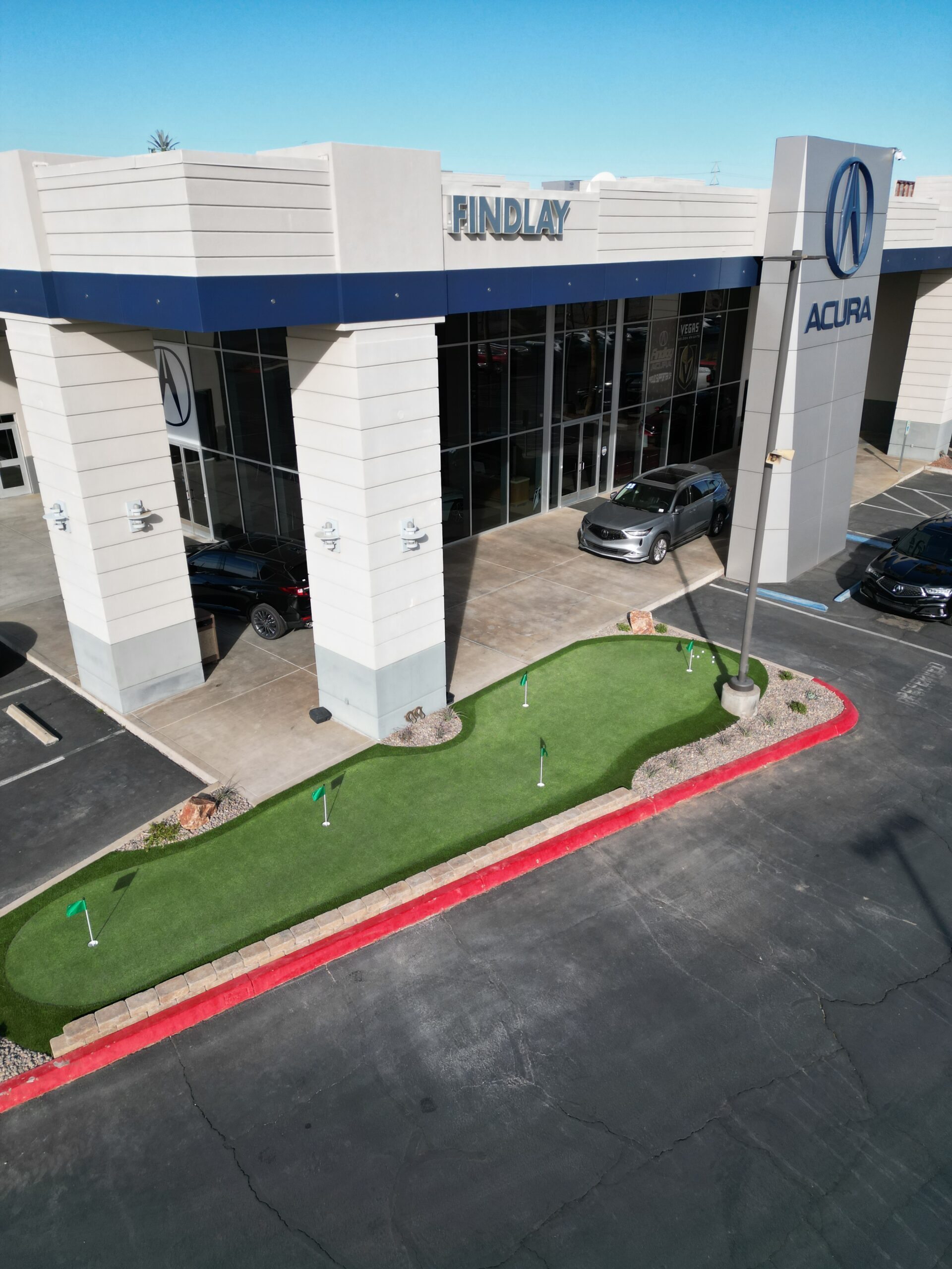 A car dealership with a putting green in the middle of it. A car dealership with a putting green in the middle of it.