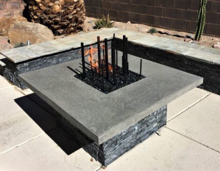 A fire pit with metal grate and stone base.