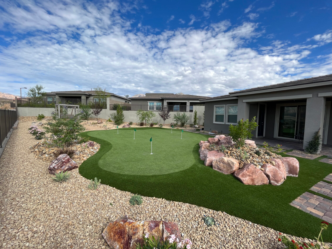 A backyard with a putting green and rocks. A backyard with a putting green and rocks.